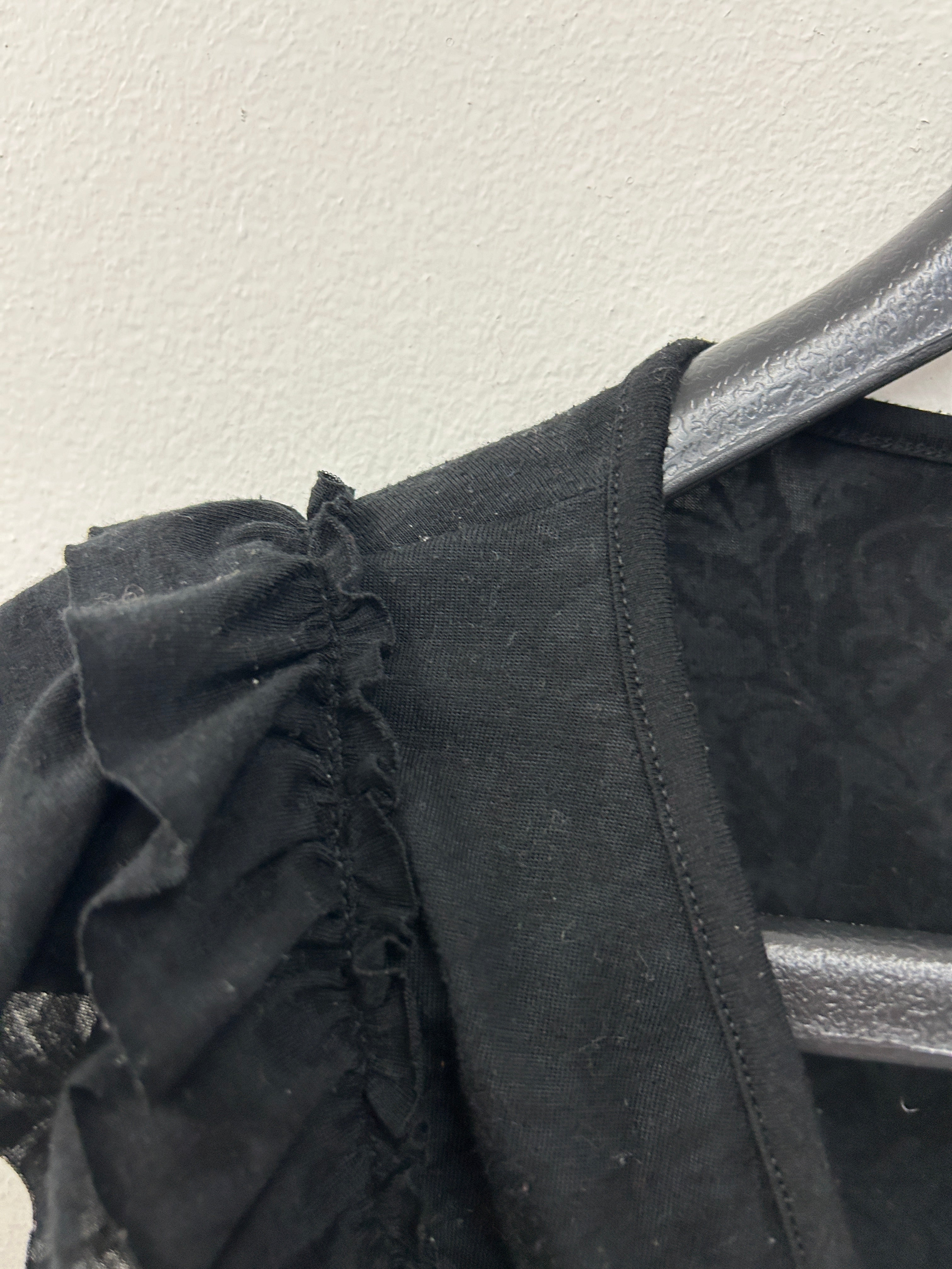 Haut cache-cœur noir à volants sur les épaules