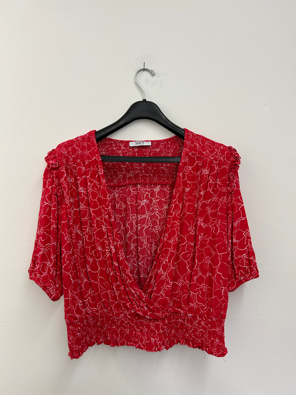 Haut rouge à fleurs croisées et taille froncée